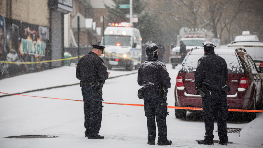 Police officers guard the perimeter of a crime scene in the winter. Photo by Andrew Burton/Getty Images.